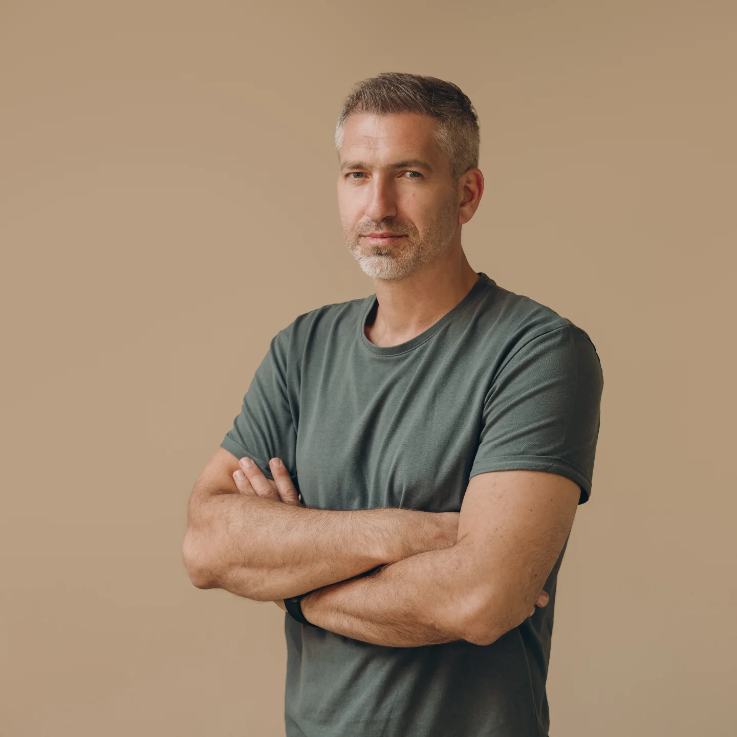 Team member portrait, arms crossed in an olive tee